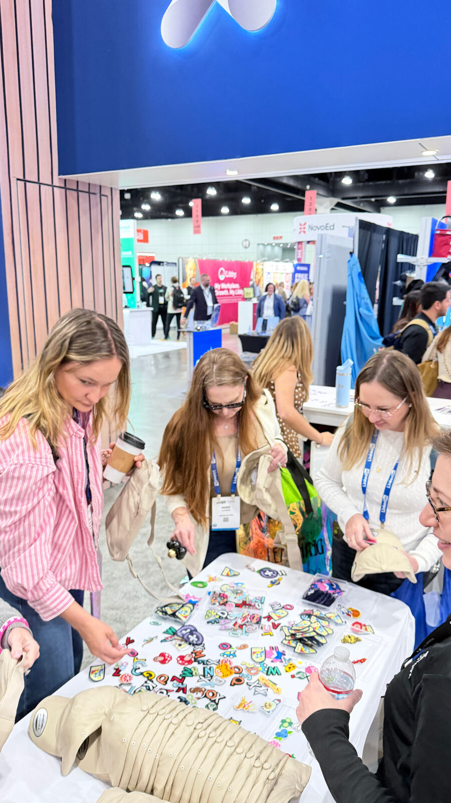 Conference booth attendees examining embroidered patch samples displayed on a white table
